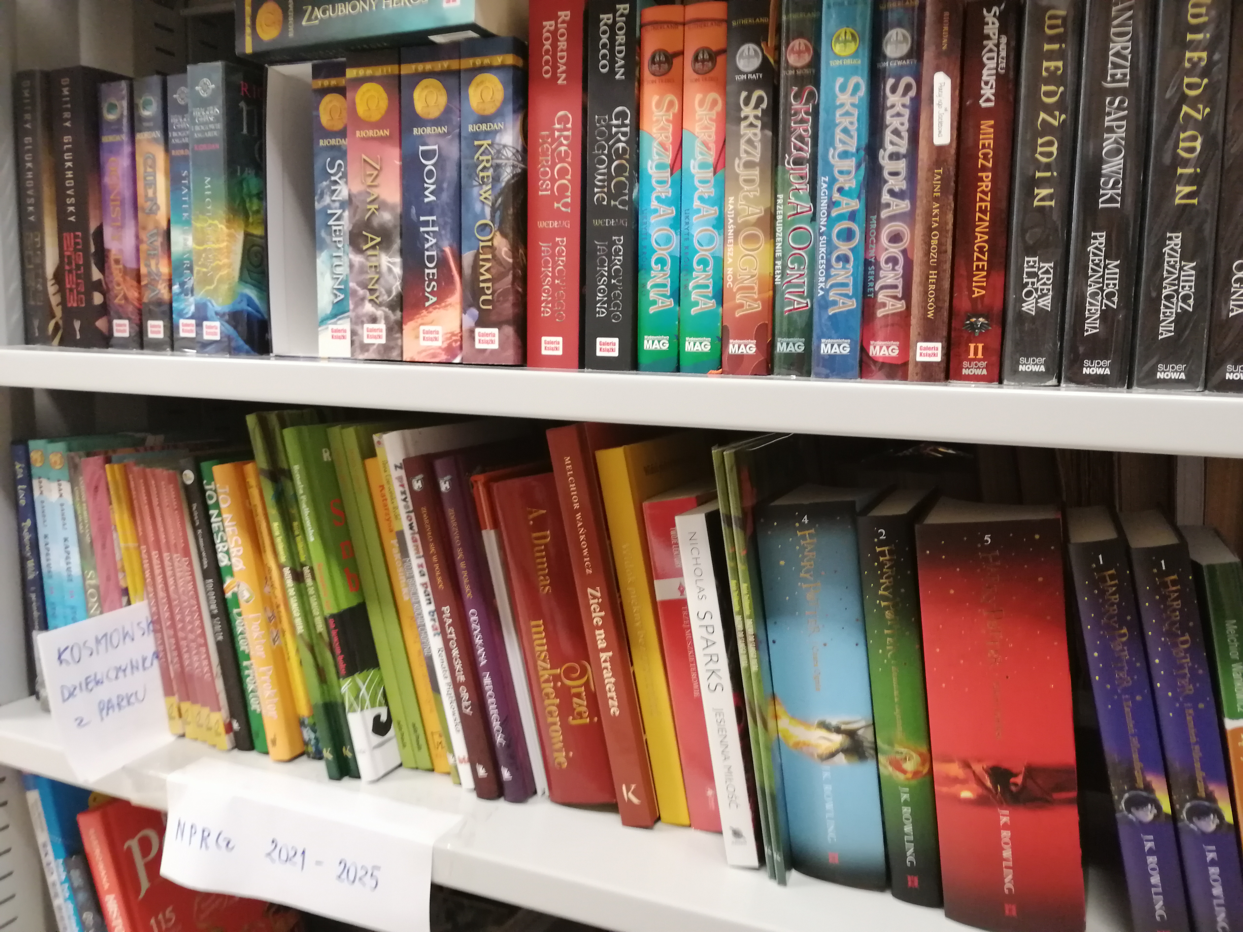 Książki dla uczniów z programu rozwoju czytelnictwa ułożone na półkach w bibliotece