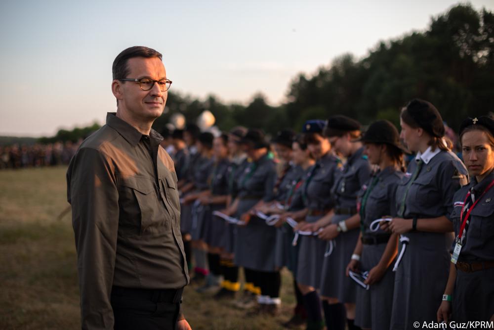 Premier Mateusz Morawiecki naprzeciwko szeregu harcerek.