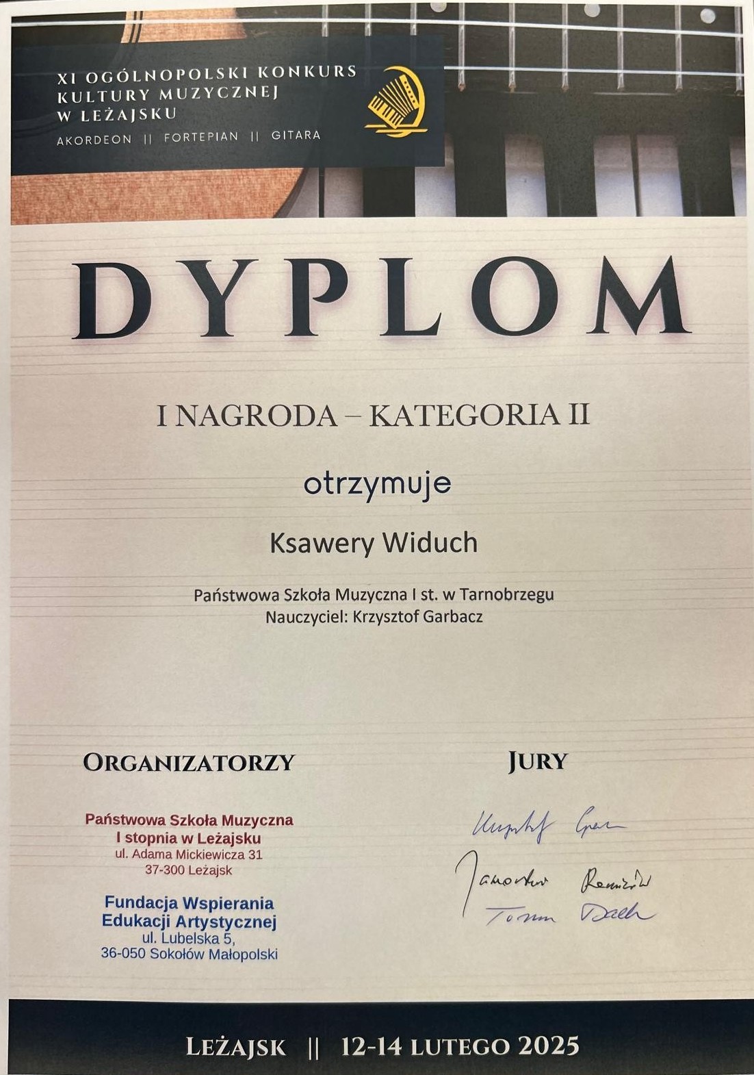 Dyplom laureata I Nagrody. Na górze znajduje się fotografia przedstawiająca fragmenty gitary i klawiatury. Po środku nazwisko laureata oraz nauczyciela. Na dole po prawej stronie znajdują się organizatorzy, a po prawej podpisy jury.