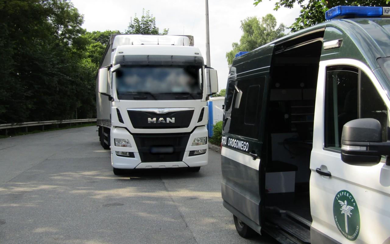 Po prawej stronie widoczny radiowóz ITD z otwartymi drzwiami, a z tyłu stoi kontrolowana ciężarówka.