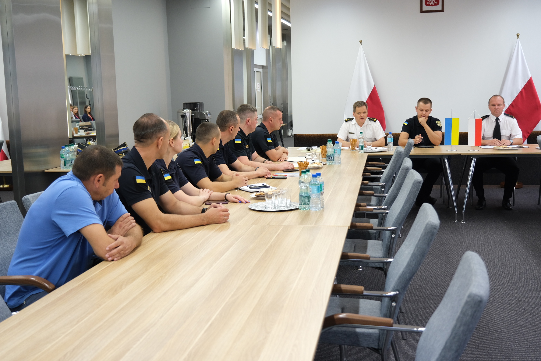 Sala konferencyjna w KG PSP za stołami ustawionymi w kształcie podkowy siedzą przedstawiciele ukraińskiej delegacji, Komendy Głównej i Szkoły Głównej Służby Pożarniczej. 