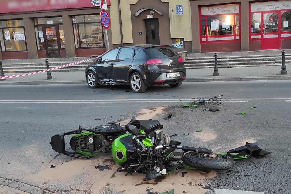 Wypadek samochodu osobowego i motocykla. Na zdjęciu wrak motocykla i samochód z rozbitym bokiem.