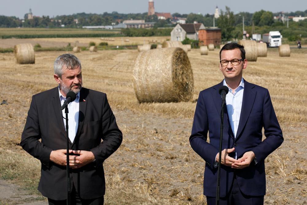 Minister J.K. Ardanowski i premier Mateusz Morawiecki, a w tle belki zboża.