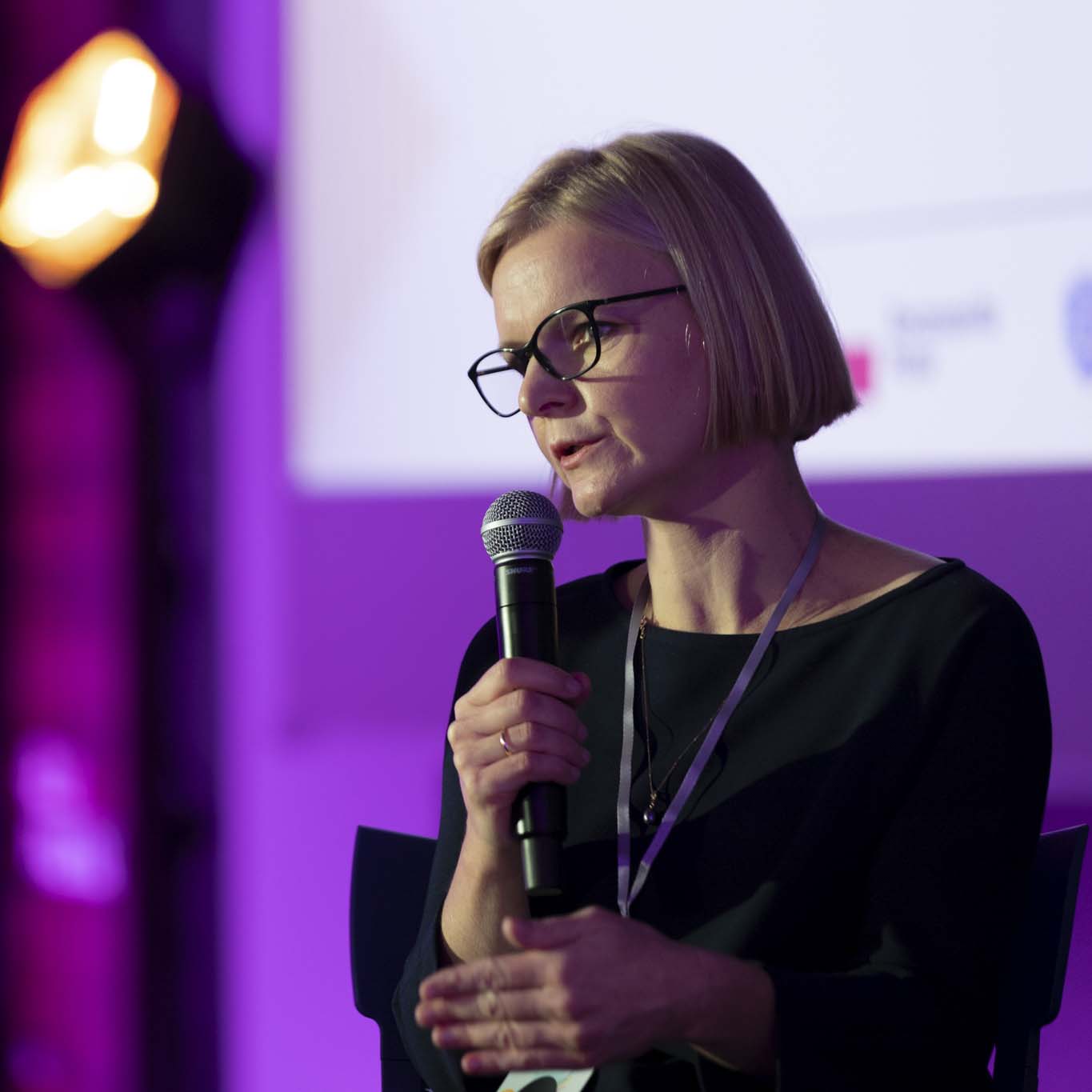 Pani Małgorzata Trębińska trzyma mikrofon i mówi do niego.