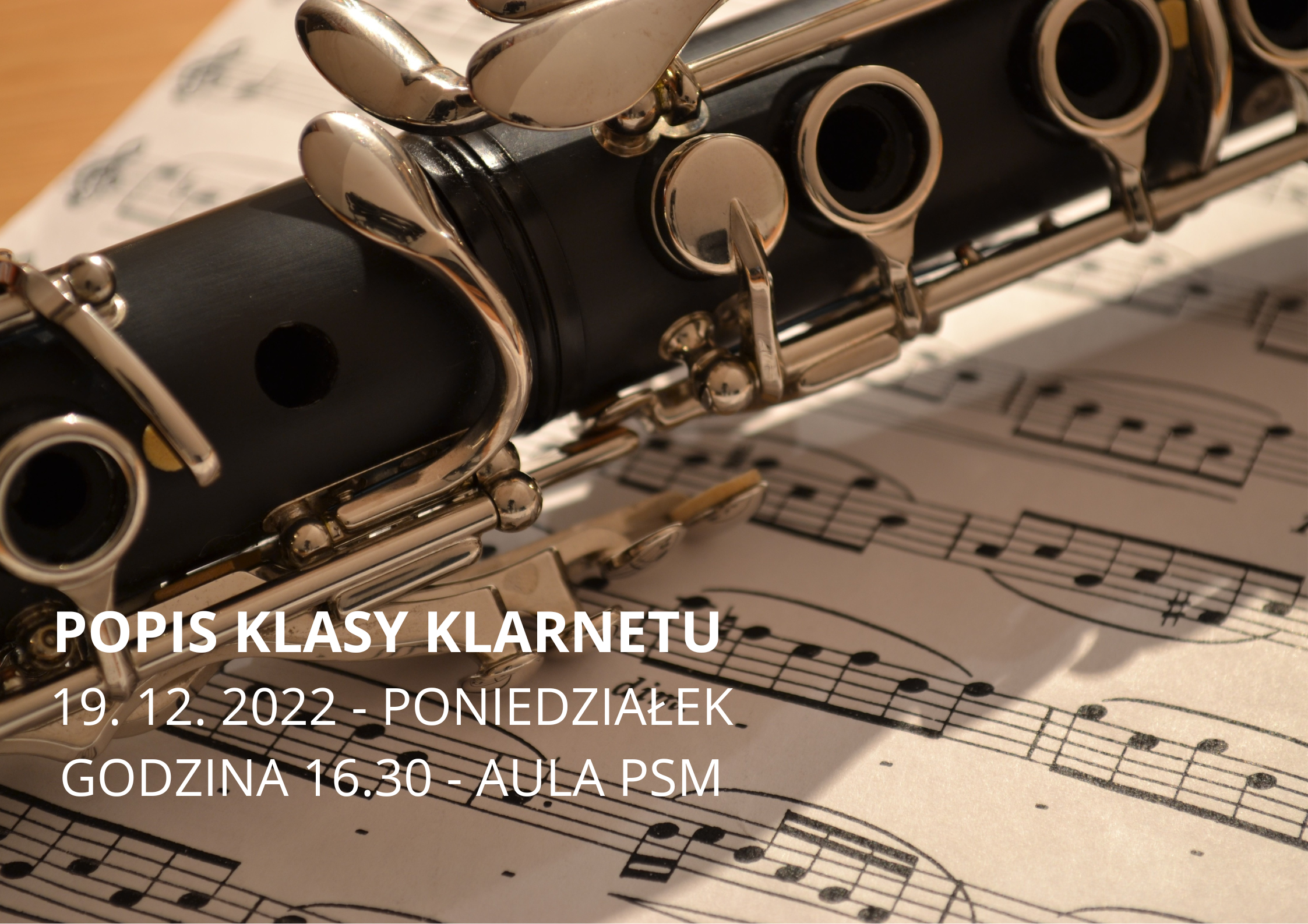 Na plakacie widać środkową część klarnetu w kolorze czarnym, w tle kartka z nutami, lekko z lewej biały napis Popis klasy klarnetu 19. 12. 2022 - poniedziałek godzina 16.30 - aula PSM