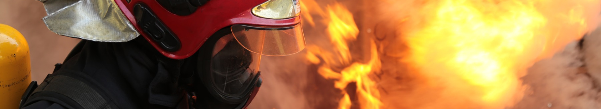 Szkolenia strażaków - strażak w aparacie ochrony dróg oddechowych, w tle rozwinięty pożar