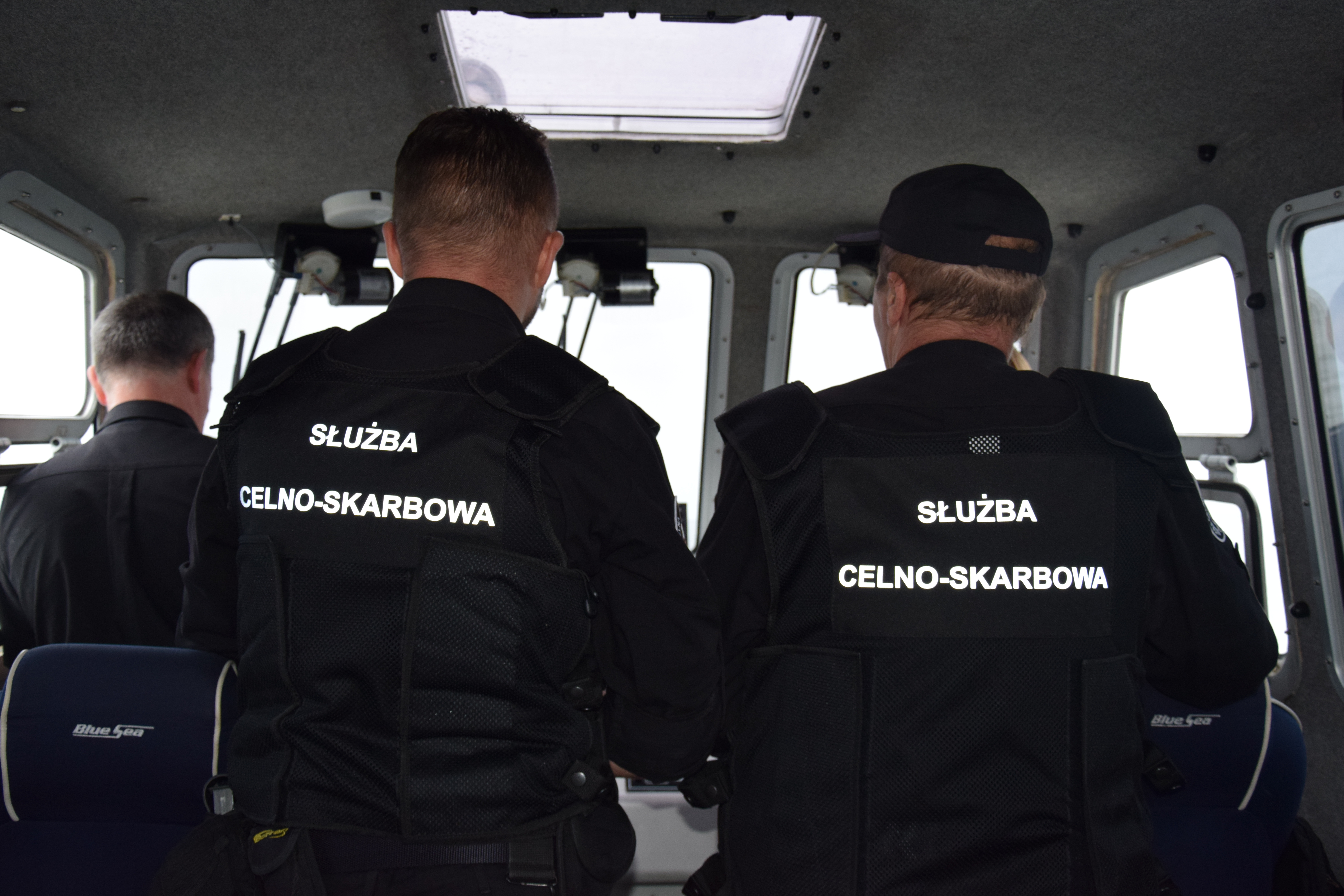 Funkcjonariusze w czarnych mundurach na łodzi patrolowej