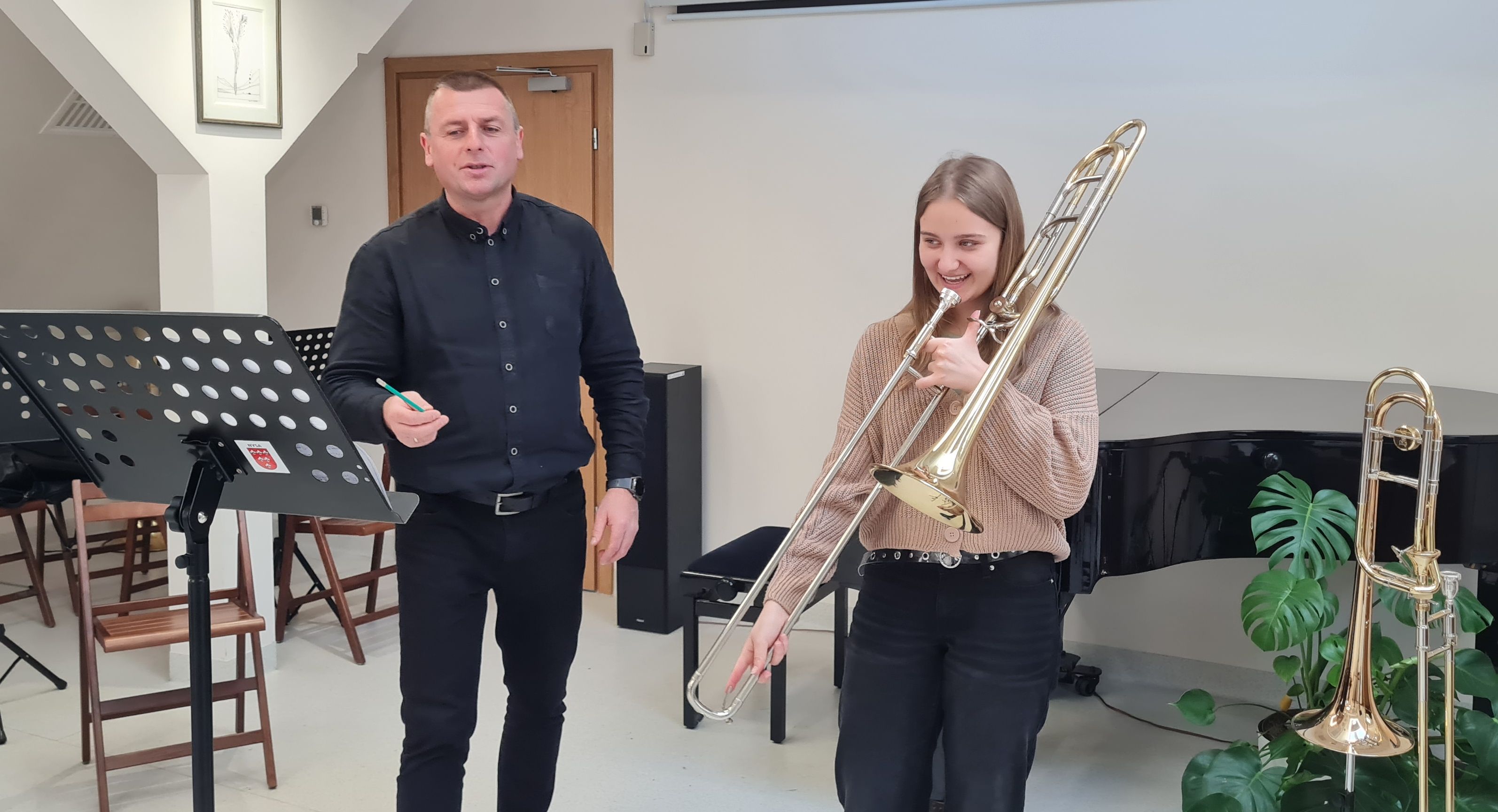 Zdjęcie. Nauczyciel prowadzący daje uwagi uczennicy grającej na puzonie. 