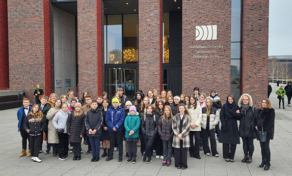 Zdjęcie przedstawiające uczniów i nauczycieli Państwowej Szkoły Muzycznej I i II stopnia w Limanowej przed budynkiem Narodowej Orkiestry Symfonicznej Polskiego Radia w Katowicach.