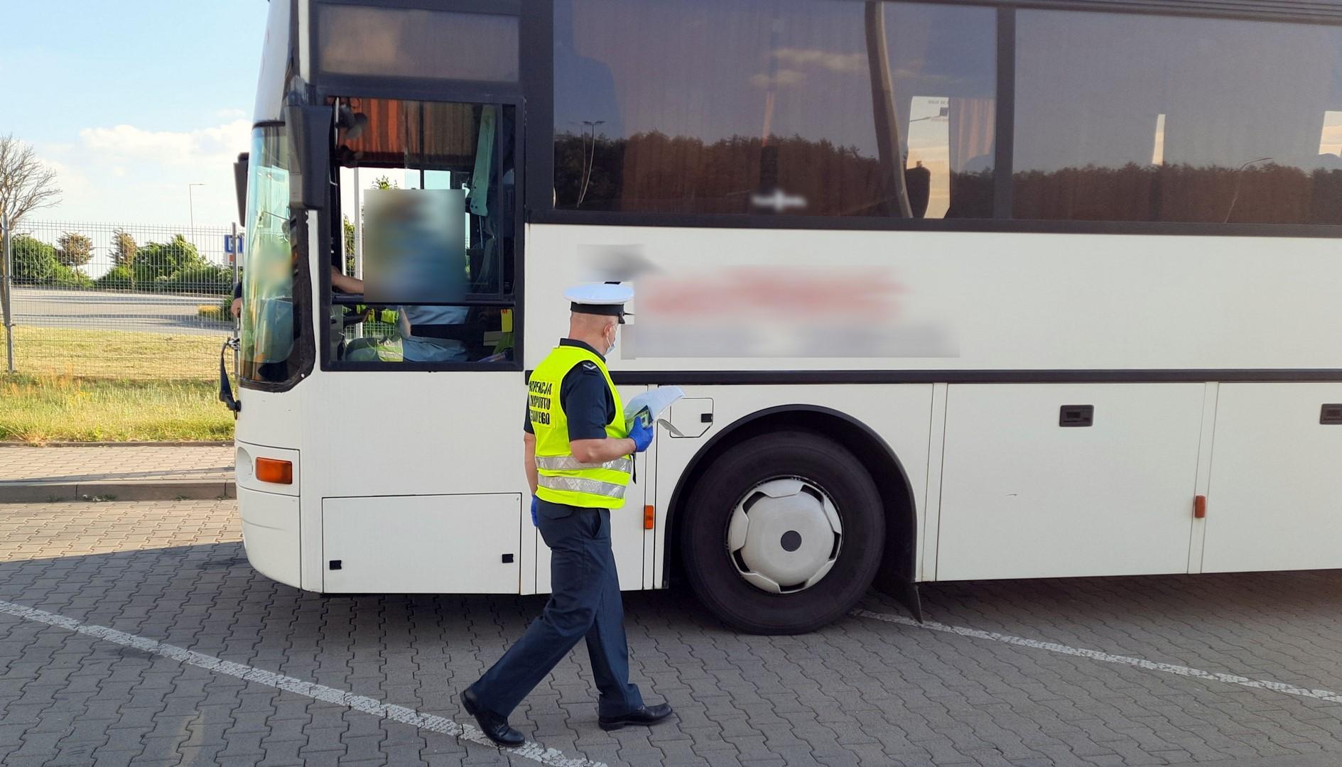 Inspektor przechodzi koło kontrolowanego autobusu.