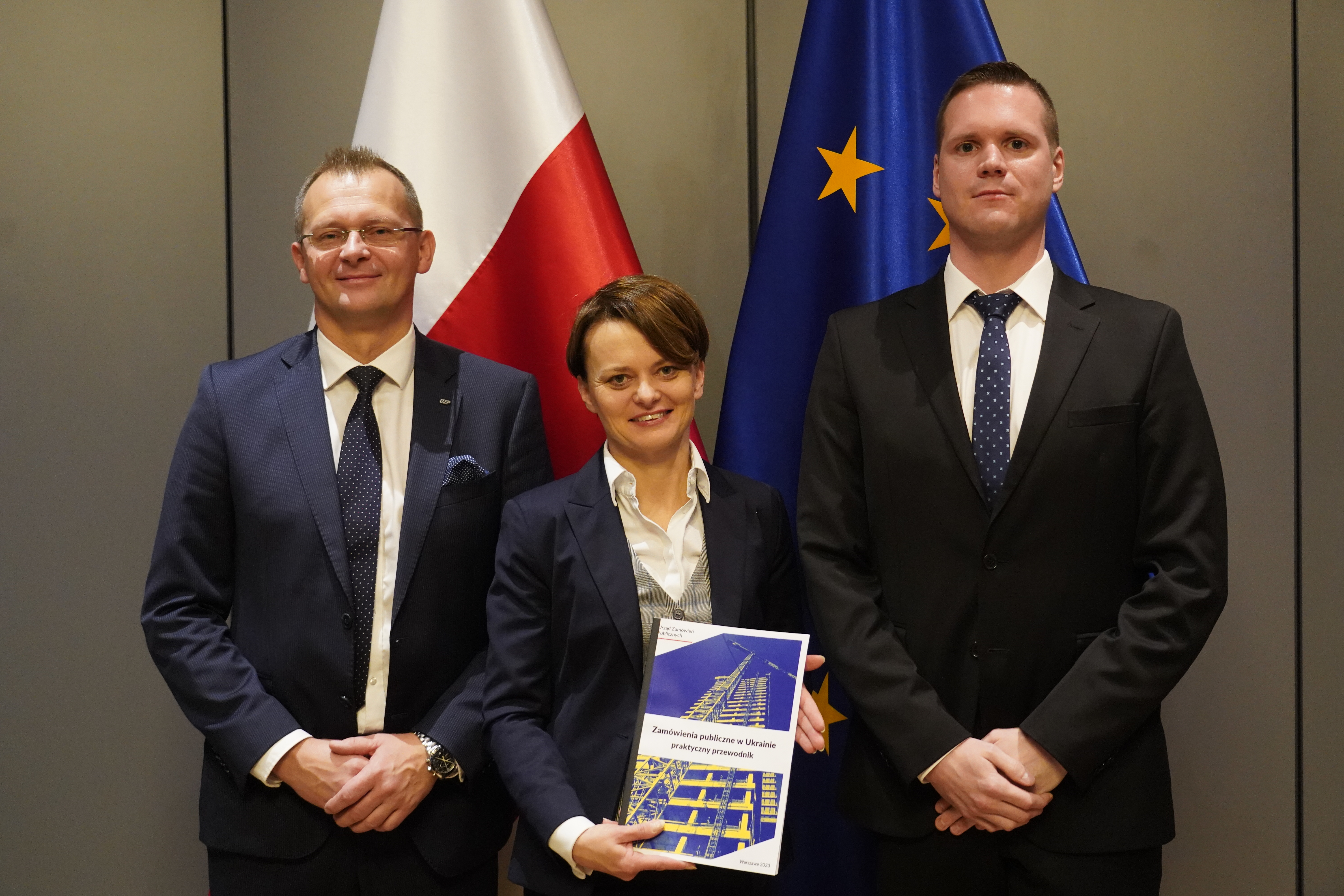 Wiceminister Jadwiga Emilewicz trzyma w rękach dokument - Zamówienia publiczne w Ukrainie praktyczny przewodnik