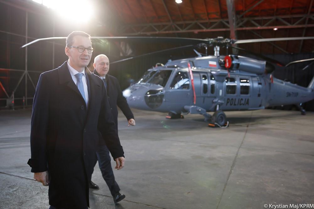 Premier Mateusz Morawiecki i minister Joachim Brudziński idą, a w tle śmigłowiec.