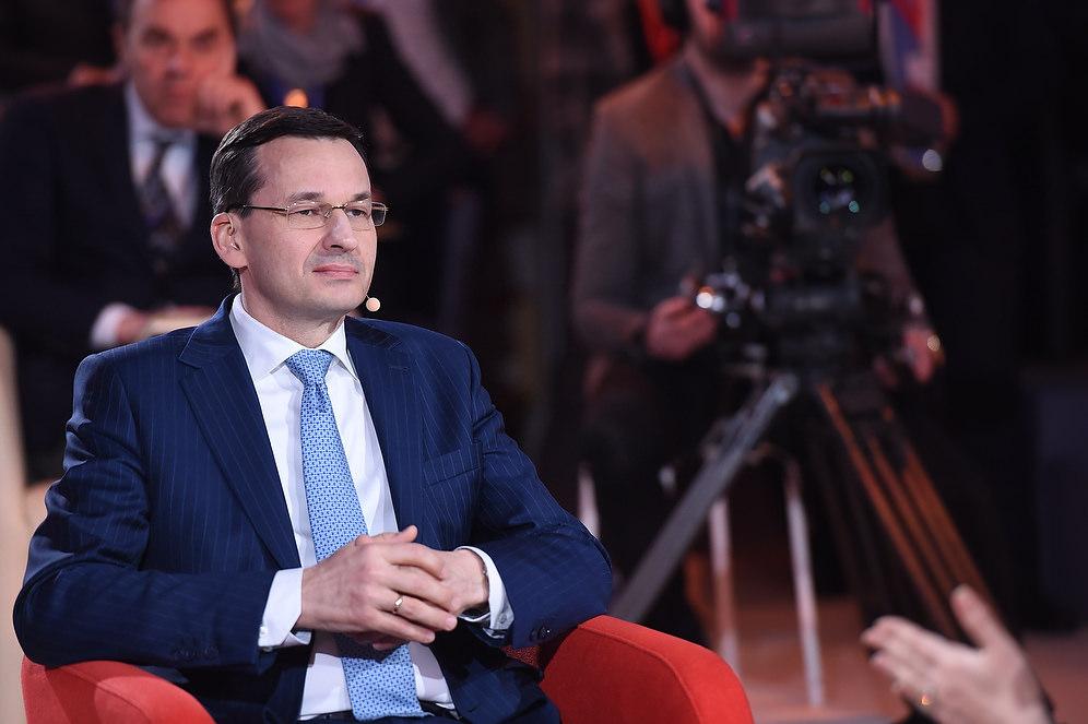 Premier Mateusz Morawiecki siedzi na fotelu. 