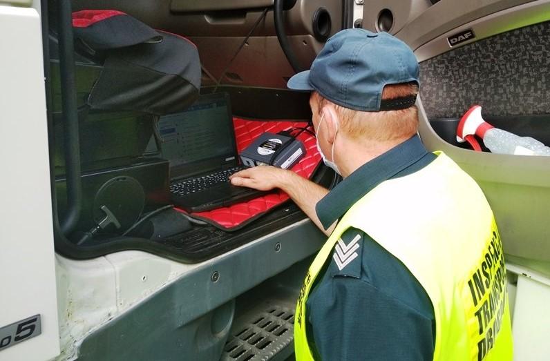 Inspektor kontroluje ciężarówkę używając nowoczesnego sprzętu diagnostycznego.