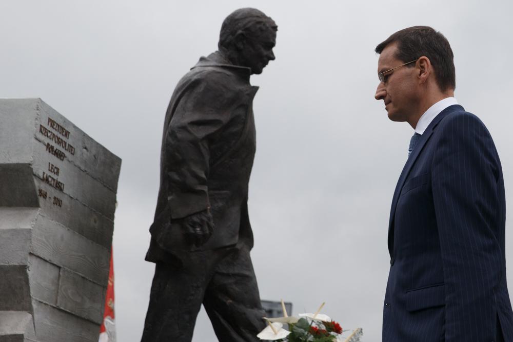 Premier Mateusz Morawiecki pochyla głowę przed pomnikiem.
