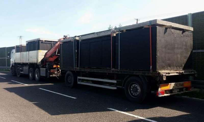 Ciężarówka z przyczepą przewożąca pięć betonowych szamb