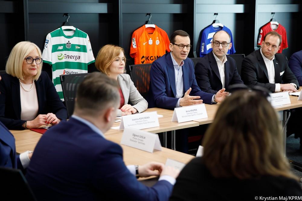 Premier wraz z uczestnikami obrad przy stole.