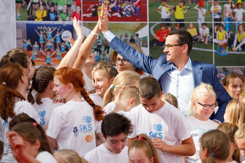 Premier Mateusz Morawiecki przybija piątkę z dziećmi.