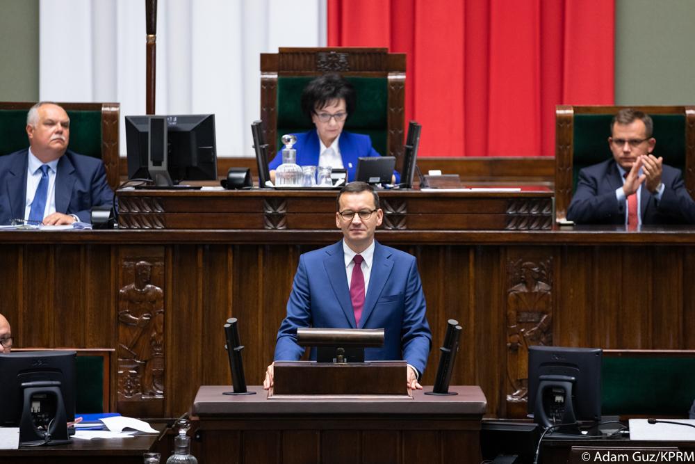 Premier Mateusz Morawiecki stoi przy mównicy, ujęcie z bliska. 