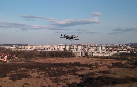 Zdjęcie drona wielowirnikowego w trakcie wykonywania pomiarów profili pionowych atmosfery na obrzeżach miasta Krakowa.