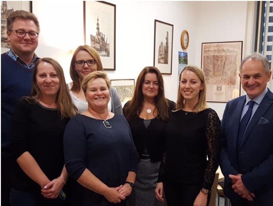 Grupa ludzi pozująca do zdjęcia w pokoju z obrazami