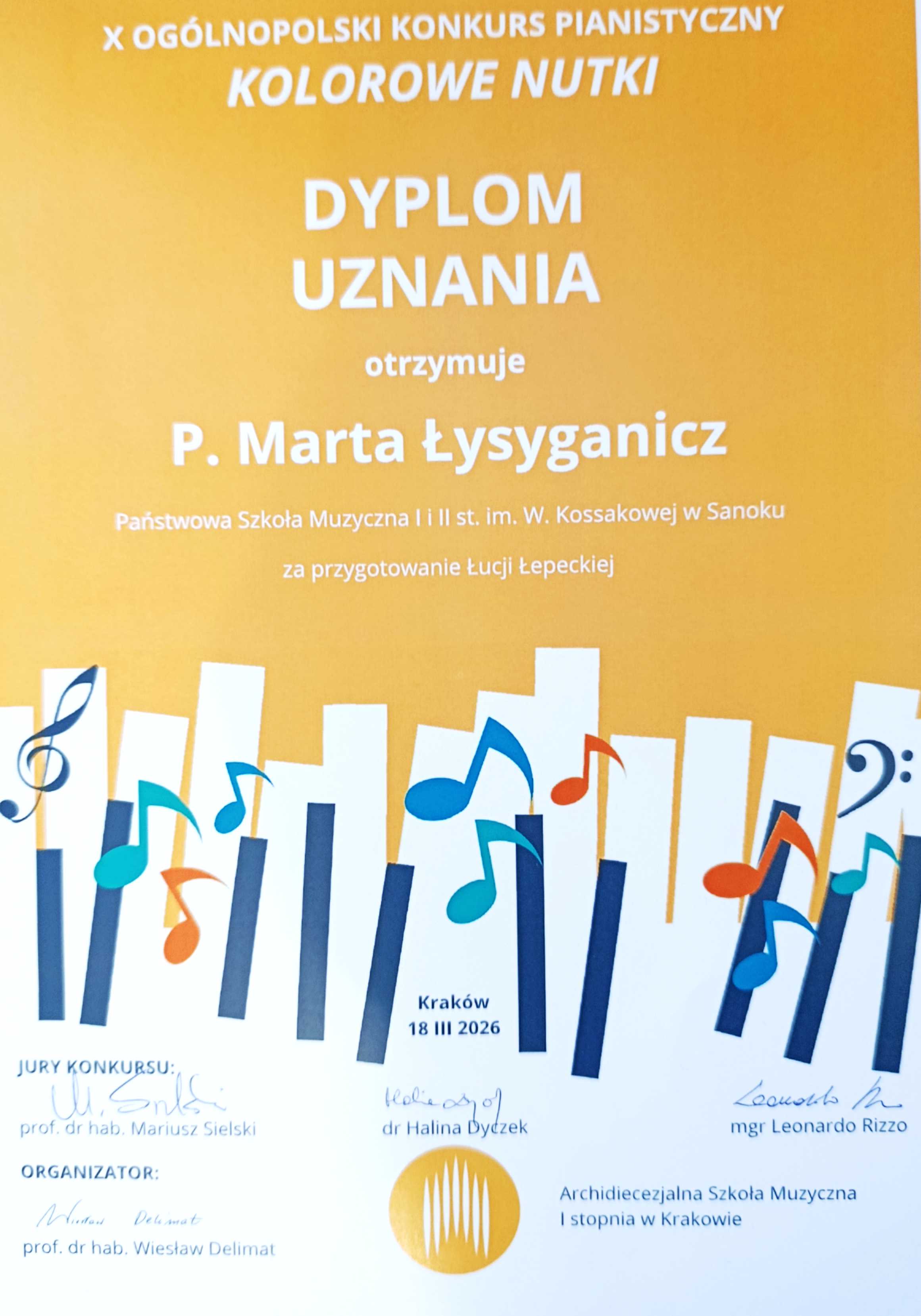 Dyplom uznania za przygotowanie ucznia dla pani Marty Łysyganicz. Białe litery na pomarańczowym tle, na dole kolorowe nutki