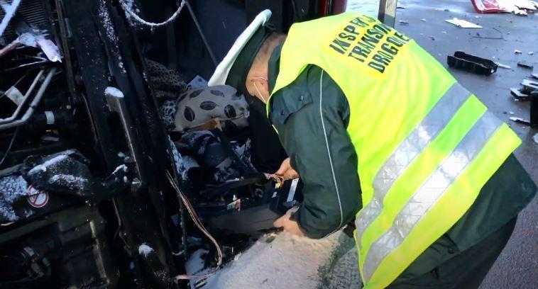 Inspektor wymontowuje tachograf z rozbitej ciężarówki