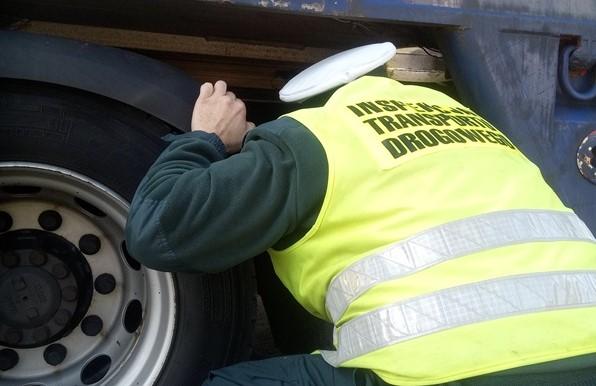 Inspektor kontroluje stan techniczny naczepy.