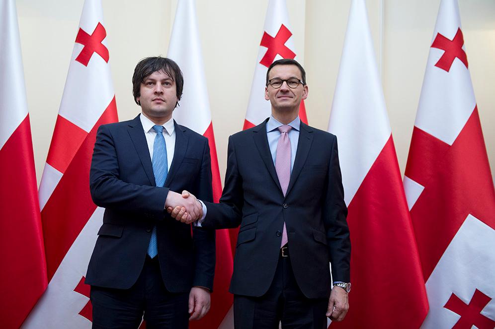 Premier Mateusz Morawiecki z z Iraklim Kobakhidze na tle flag Polski i Gruzji.