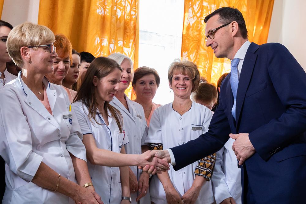 Premier Mateusz Morawiecki ściska dłoń pielęgniarce.