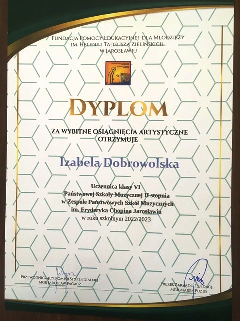 Dyplom na ozdobnym tle, ze stylizowaną na otwieraną kartę książki grafiką. Na górze napis FUNDACJA POMOCY EDUKACYJNEJ DLA MŁODZIEŻY IM. HELENY I TADEUSZA ZIELIŃSKICH W JAROSŁAWIU. Poniżej logotyp fundacji i złoty napis dużymi literami DYPLOM za wybitne osiągnięcia artystyczne otrzymuje Izabela Dobrowolska Uczennica kl. VI PSM II st. w ZPSM im. F. Chopina w Jarosławiu w roku szkolnym 2022/2023
