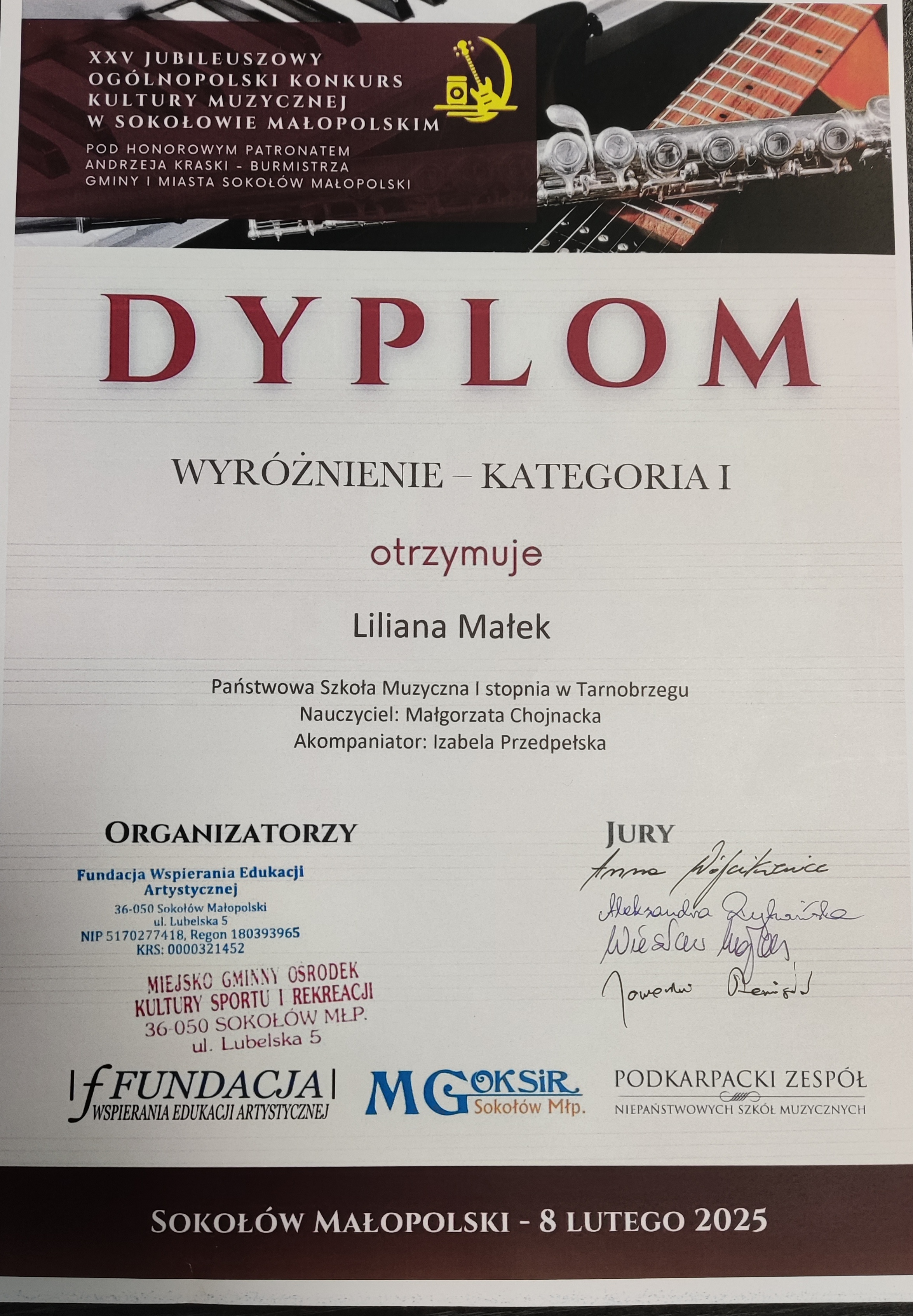 Dyplom wyróżnienia. Na górze znajduje się nazwisko patrona w brązowej ramce, a w tle zdjęcie przedstawiające fragmenty fortepianu, gitary oraz fleta poprzecznego. Po środku nazwisko otrzymującego wyróżnienie oraz nauczyciela. Na dole po lewej stronie organizatorzy, a po prawej podpisy jury. Tekst w kolorze czerwonym i czarnym.
