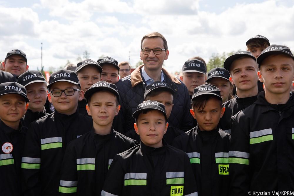 Premier Mateusz Morawiecki pozuje do zdjęcia z młodymi strażakami.