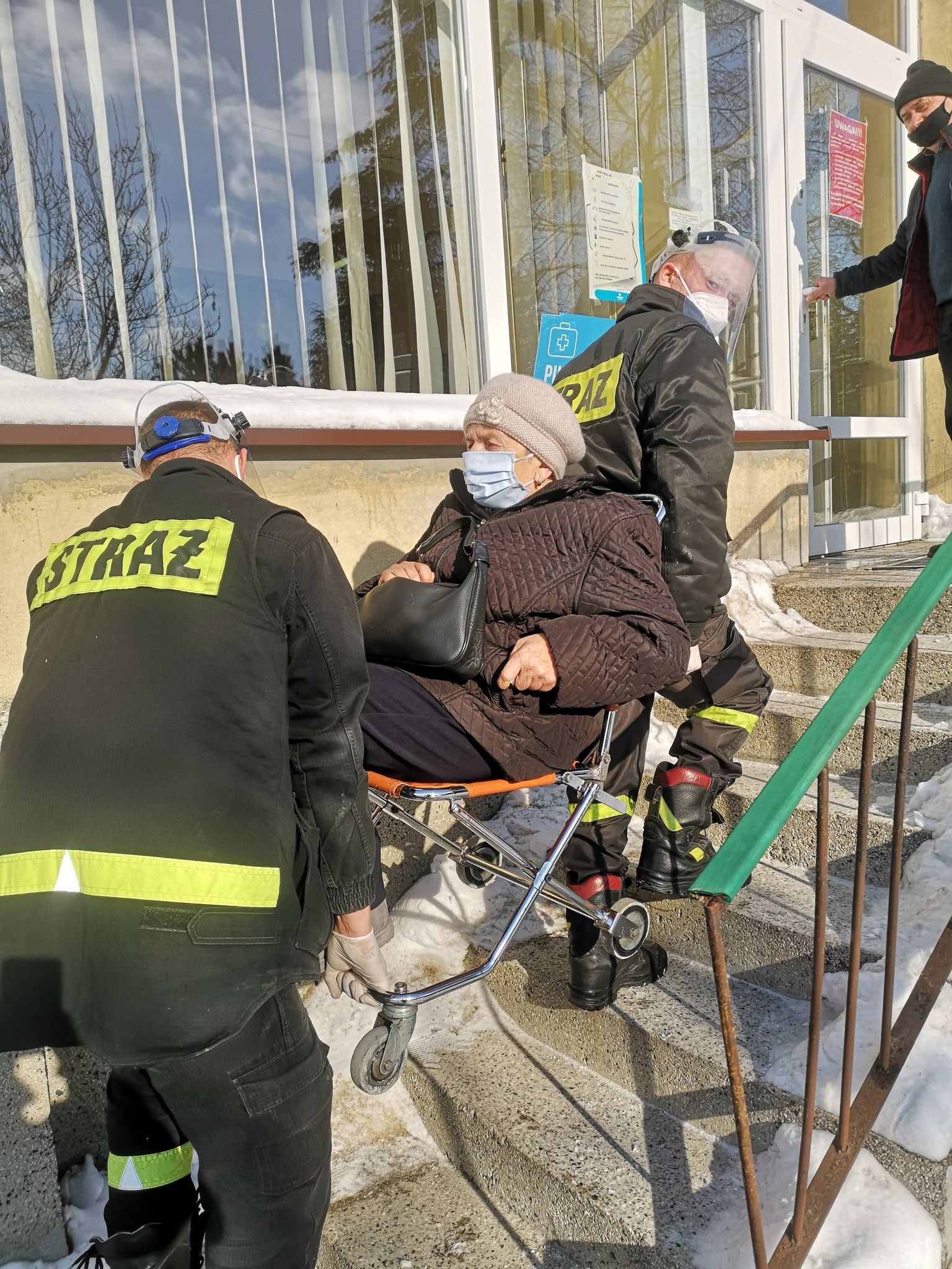 strażacy wnoszą seniorkę
