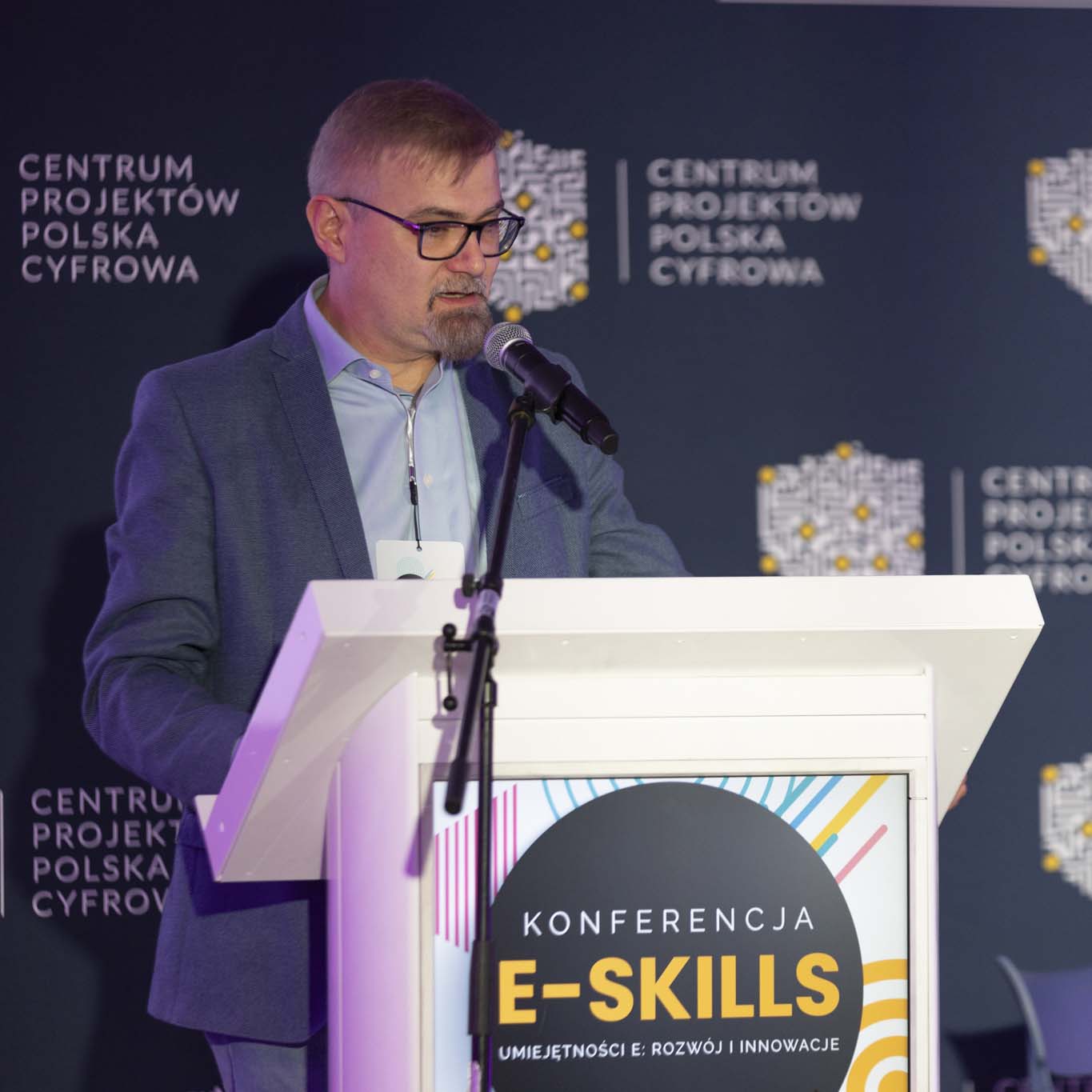 Przy mównicy stoi profesor Jacek Marciniak. Wzrok kieruje w dół. Mówi do mikrofonu.