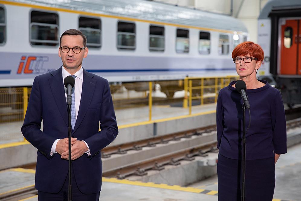 Premier Mateusz Morawiecki i minister Elżbieta Rafalska stoją przy mikrofonach.