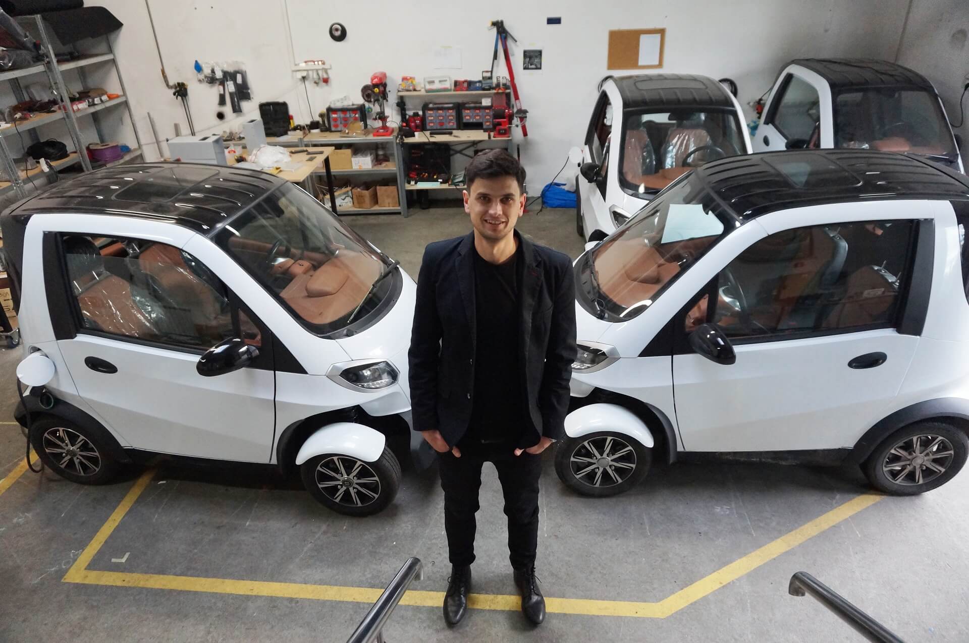 Doktor Maciej Wieczorek stoi w warsztacie na tle biało-czarnych aut