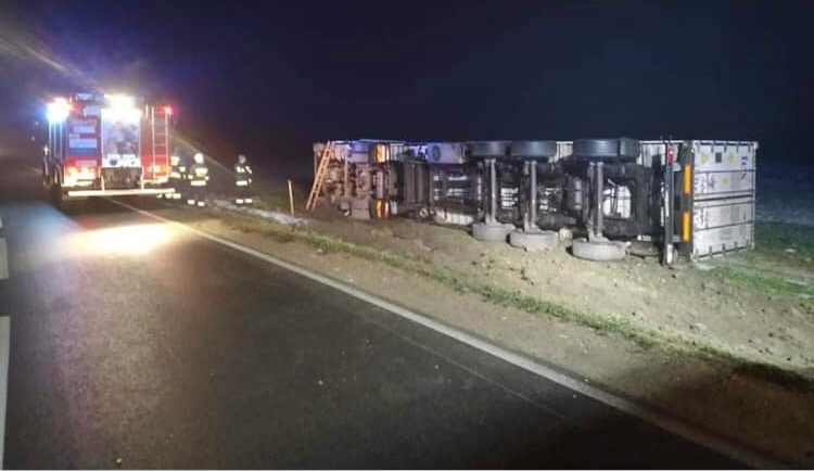 Wypadek samochodu ciężarowego. Pojazd leży na prawym boku obok jezdni.