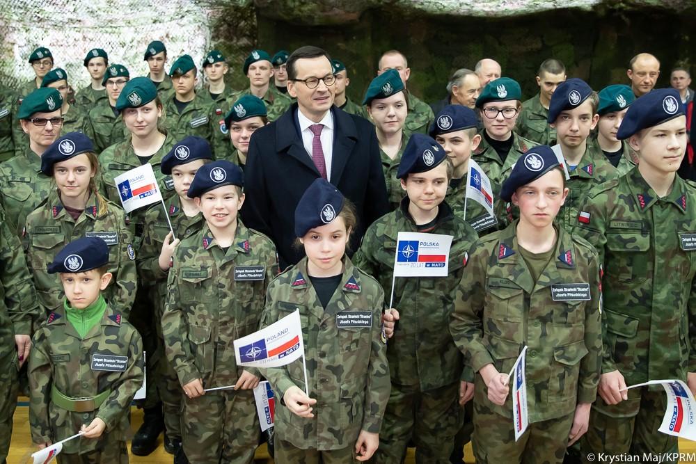 Wspólne zdjęcie premiera Mateusza Morawieckiego z młodzieżą ubraną w wojskowe stroje.