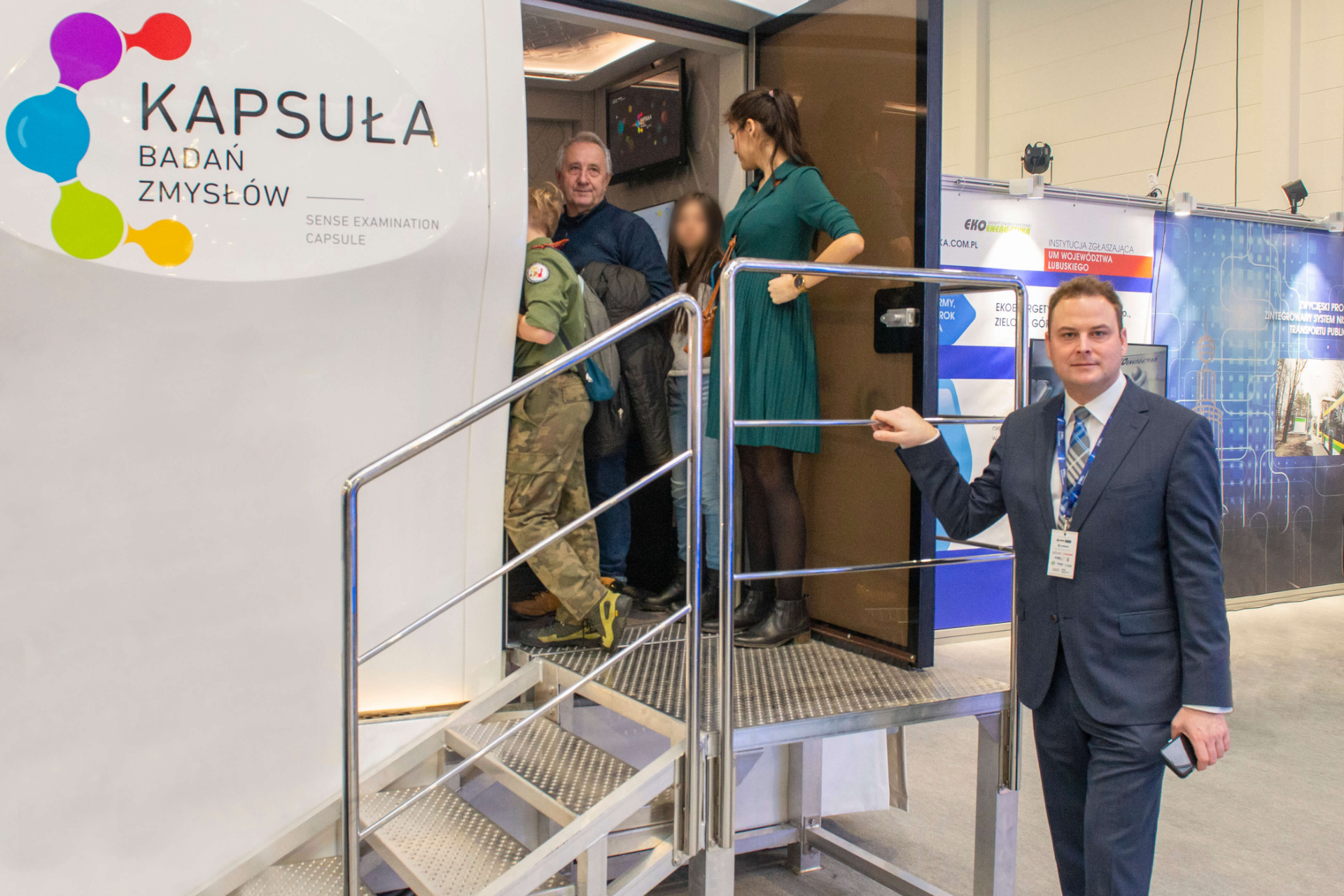 Paweł Doliński, M.Sc., stands in front of the Diagnostic Capsule, into which several people enter