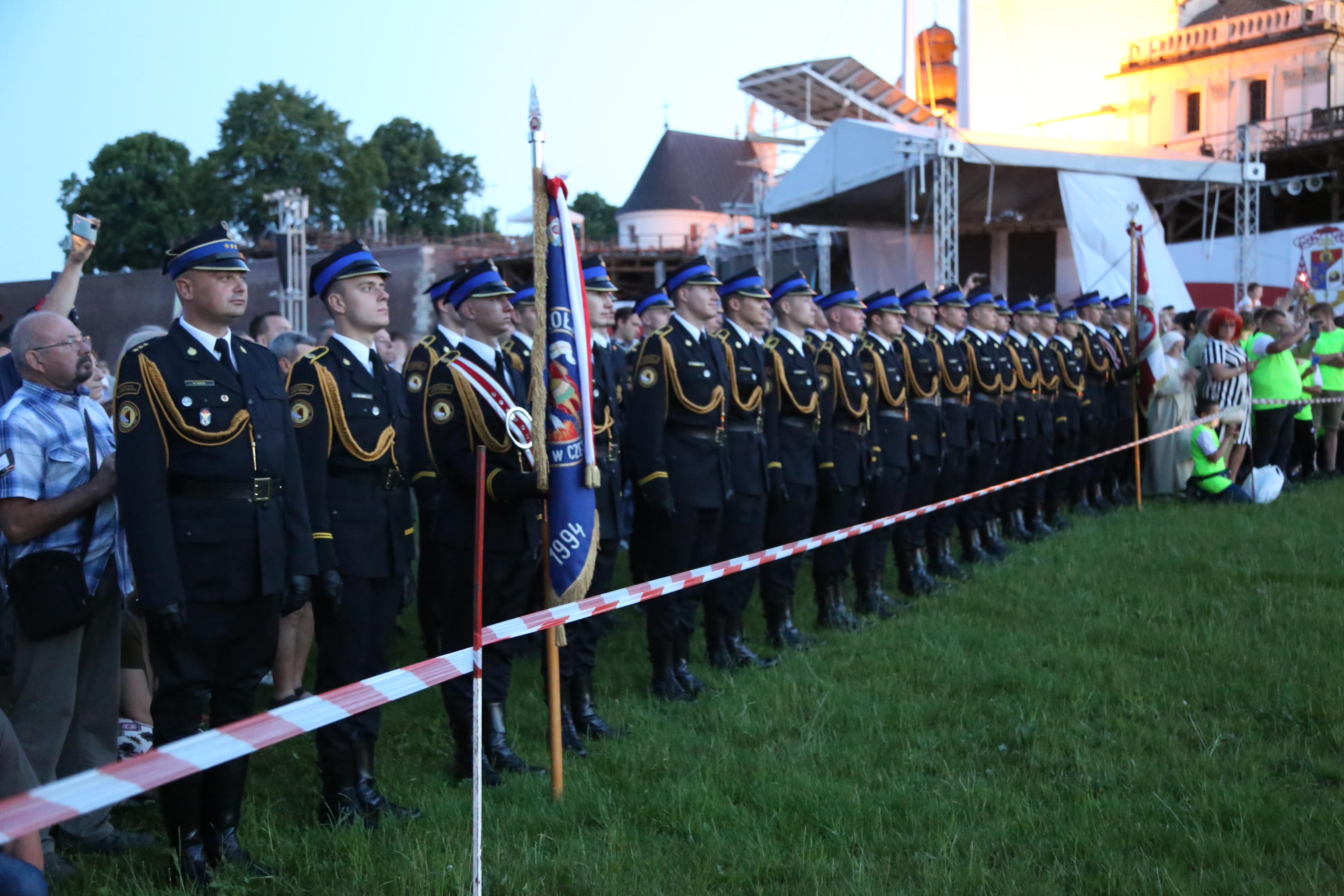 Na Błoniach Jasnogórskich ustawieni w szeregu strażacy wraz ze sztandarem