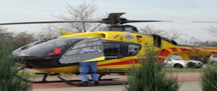 Zdjęcie przedstawia stojący śmigłowiec Lotniczego Pogotowia Ratunkowego. Przy otwartych drzwiach stoi pilot.