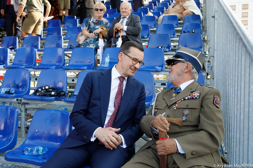 Premier siedzi i rozmawia z kombatantem.