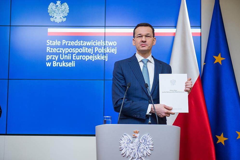 Premier Mateusz Morawiecki pokazuje Białą Księgę. 