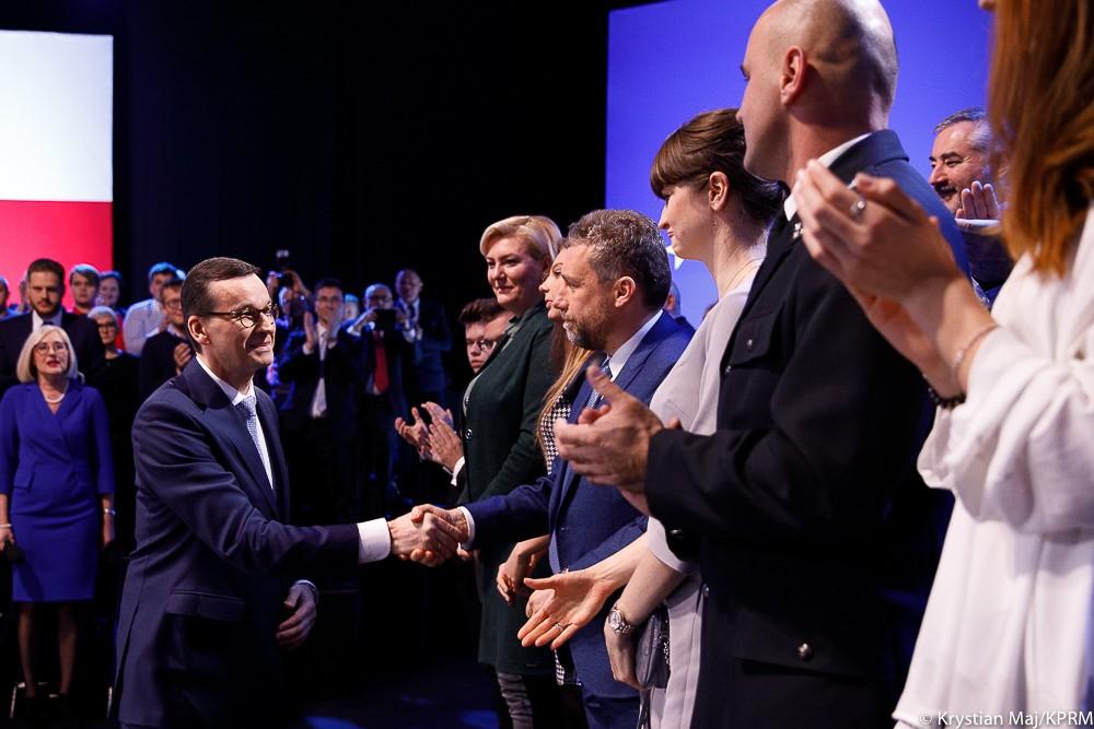 Premier Mateusz Morawiecki ściska rękę uczestnikowi konferencji. 