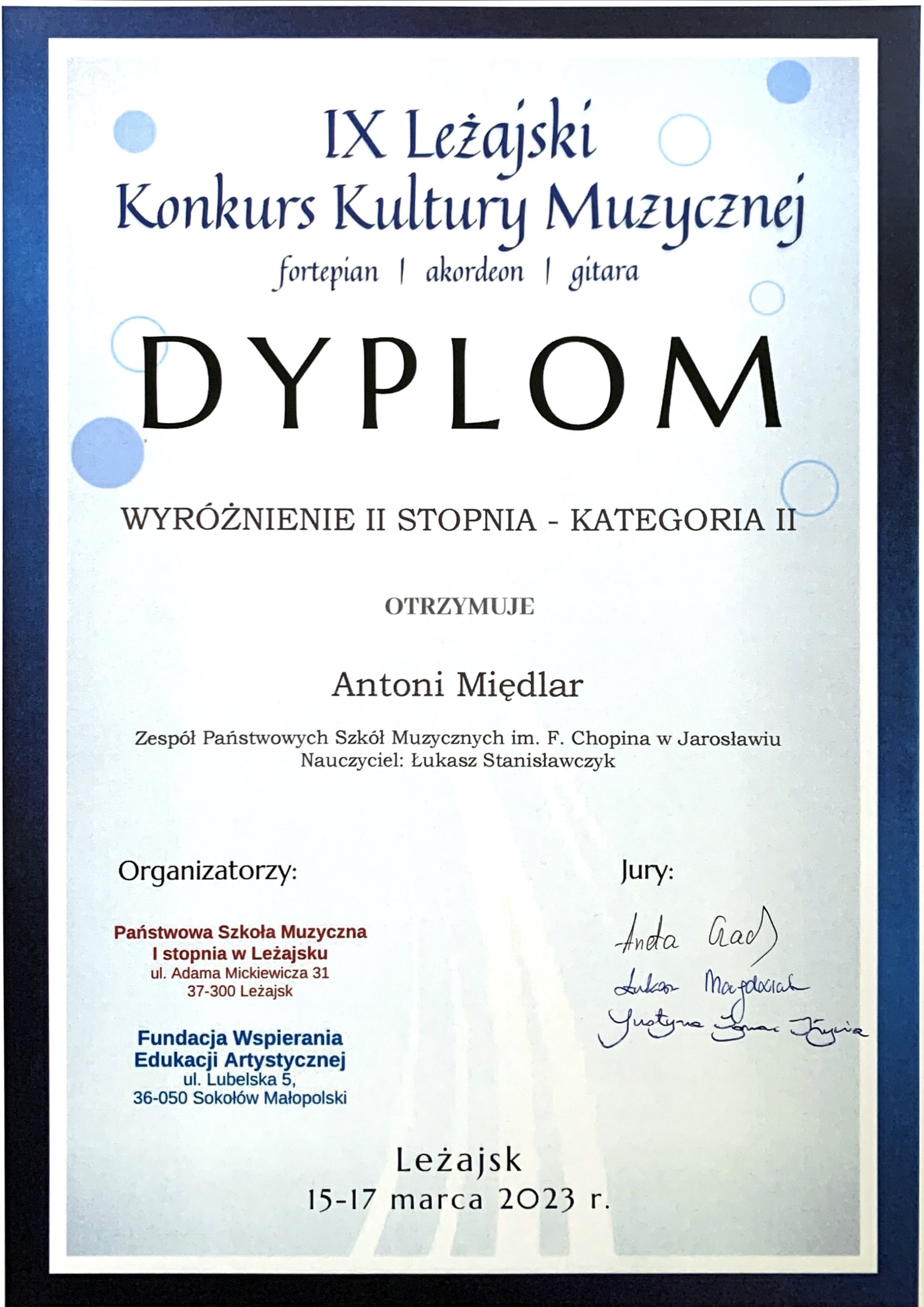 Dyplom konkursu na białym tle z granatowym obramowaniem, na górze granatowymi literami IX Leżajski Konkurs Kultury Muzycznej fortepian/akordeon/gitara Wyróżnienie II stopnia - kategoria II Antoni Międlar ZPSM im. F. Chopina w Jarosławiu Nauczyciel Łukasz Stanisławczyk poniżej z lewej strony pieczątki organizatorów PSM I st. w Leżajsku oraz Fundacji Wspierania Edukacji Artystycznej, po prawej podpisy członków Jury. Na dole napis Leżajsk, 15-17 marca 2023 r.