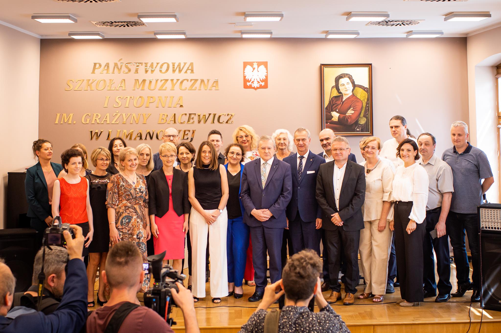 Zdjęcie Minister Kultury i dziedzictwa Narodowego Piotr Gliński w towarzystwie Dyrekcji, nauczycieli i rady rodziców PSM I stopnia w Limanowej. Zdjęcie wykonane w auli szkoły.