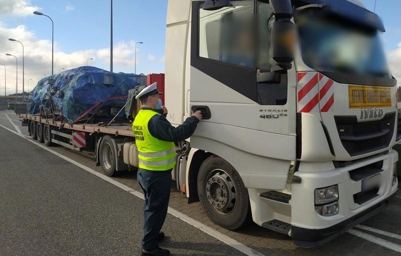 Inspektor pobiera dokumenty od kierowcy ciężarówki.