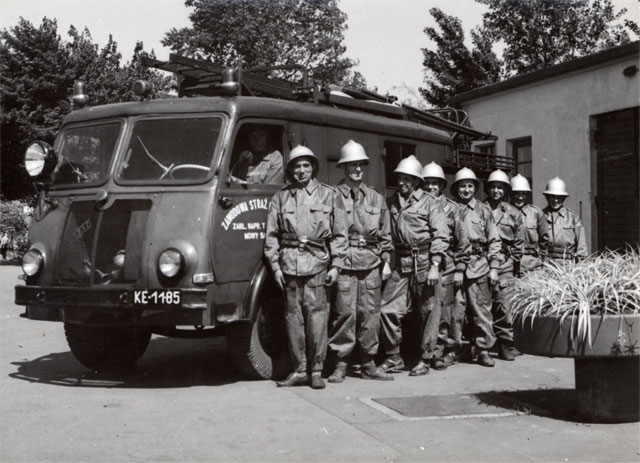 Ośmiu strażaków Zakładowej Zawodowej Straży Pożarnej ZNTK z roku 1968 stoją na tle samochodu gaśniczego marki Star.