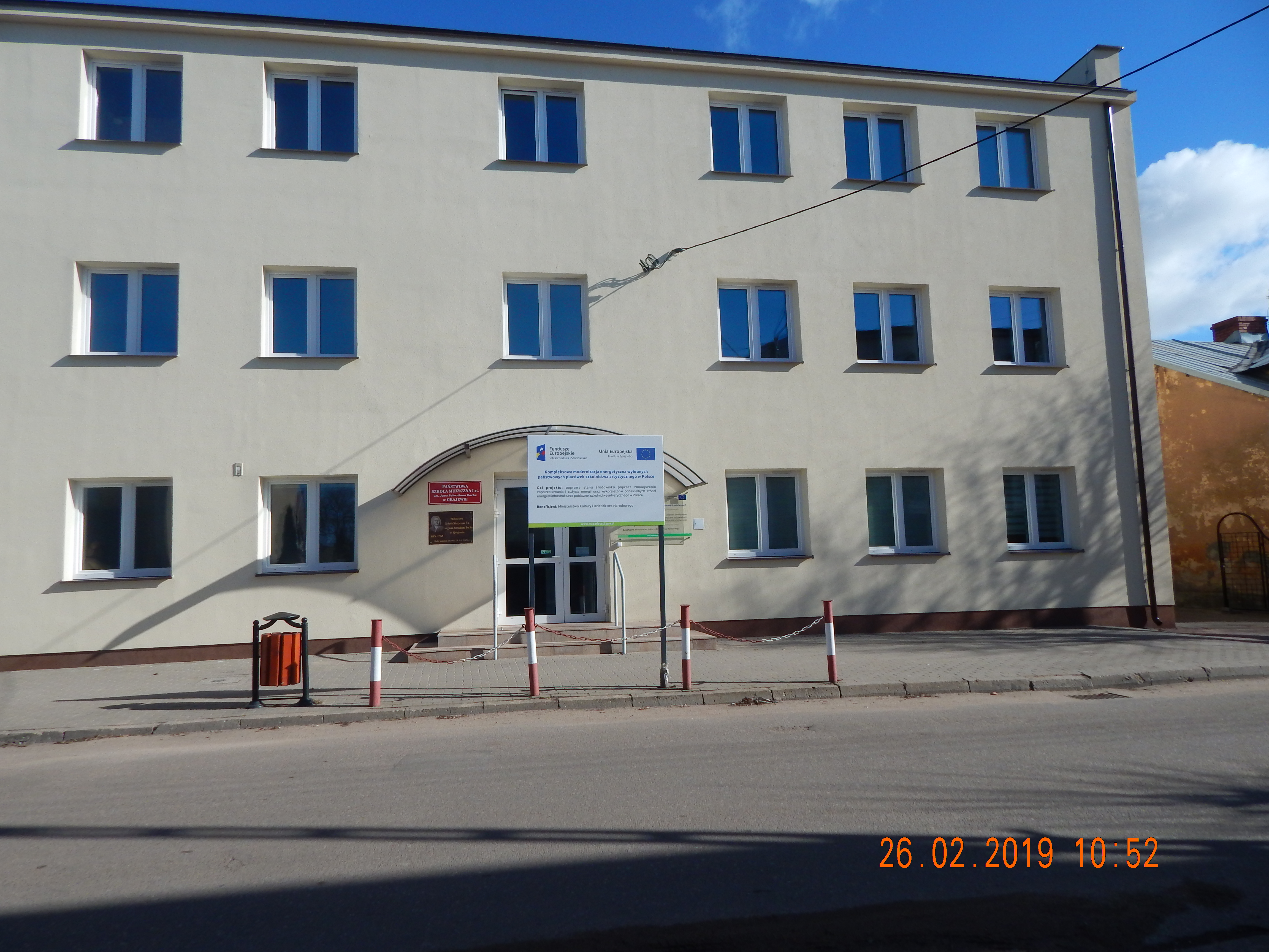 Zdjęcie budynku z zewnątrz po termomodernizacji, widok od frontu, budynek z białą elewacją. 